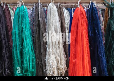 Wool yarns of different colors displayed in a row next to each other. red, green, blue, gray, white, brown woolen threads. group of rows of wool on lo Stock Photo