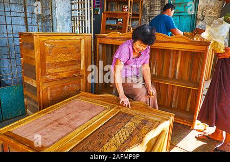 YANGON, MYANMAR - FEBRUARY 17, 2018: The elderly female carpenter  at work in family workshop, located in Chinatown, on February 17 in Yangon Stock Photo