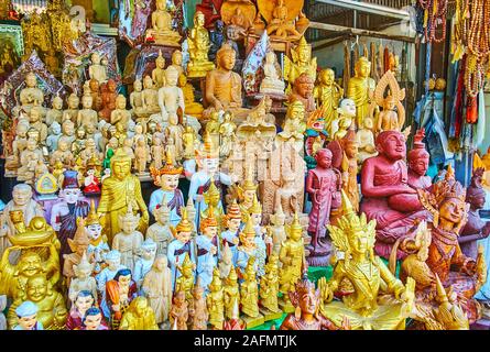 The showcase of traditional market stall with large amount of Buddhist cult pieces - figurines of Nats spirit deities, Buddha images, protective statu Stock Photo