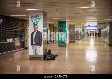 Homeless man sleeping on floor of subway concourse, Philadelphia, USA Stock Photo