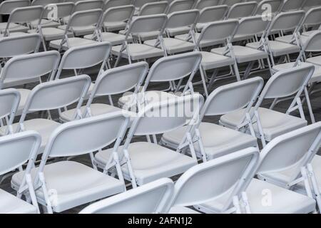 Rows of white padded folding chairs in auditorium Stock Photo