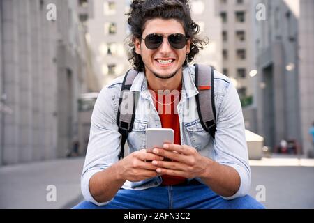 Young adult man smiling and using smartphone Stock Photo
