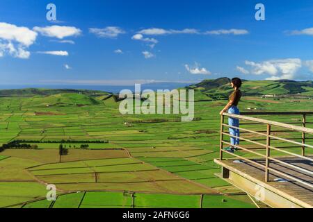 Young women enjoying the View of Terceira Island with bright Blue Sky and Ocean from Miradouro Serra do Cume in Terceira Island, Azores Stock Photo
