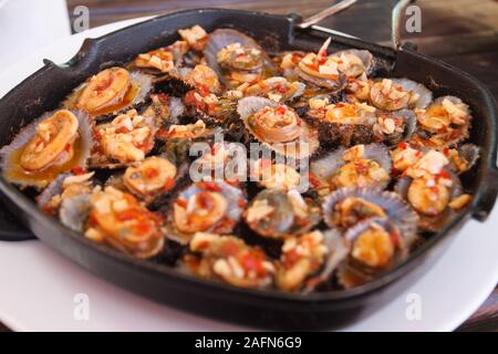 Grilled limpets or Lapas served in cast iron pan, A delicacy of Azores islands. Stock Photo