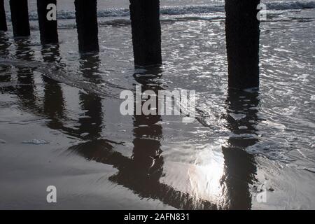 Reflections of the sun on the sand and the sea showing a rich texture and beautiful patterns on the south coast of England. Stock Photo