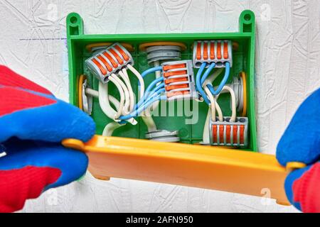 Connecting electrical wires with a clamp connector. Splicing cables inside the distribution box using a terminal block with lever clamps and spring. A