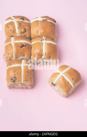 Six hot cross buns, traditional British Easter food on pink background, top view, toned, selective focus Stock Photo