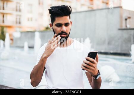 Young indian man shocked read on the phone in the street Stock Photo