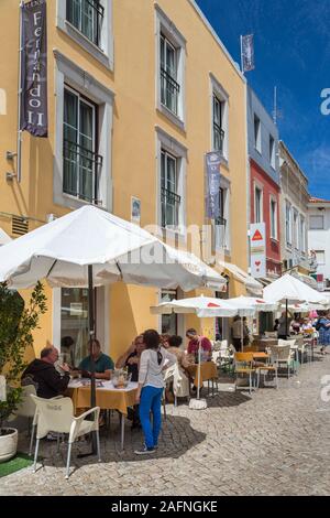 People sitting at restaurant tables and chairs in street, Loule, Algarve, Portugal Stock Photo