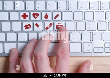 Choosing the necessary medical care online. Hand on the keyboard with signs. Close up. Stock Photo