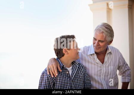 Mature man sitting on the hotel balcony with his son. Stock Photo