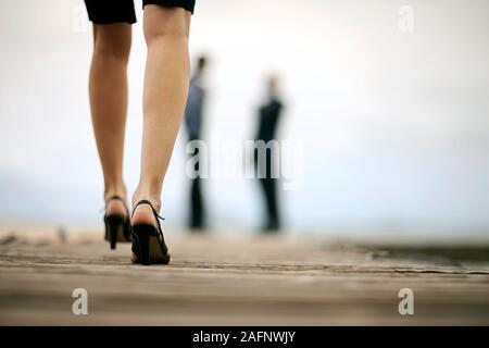 Mid-adult businesswoman walking on the pier towards her business partners. Stock Photo