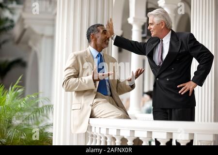 Two adult businessmen having a discussion on a porch. Stock Photo