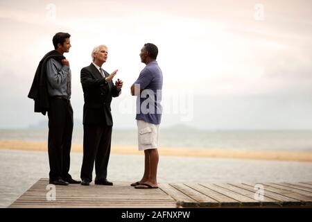 Three men having a discussion on a jetty. Stock Photo