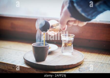 https://l450v.alamy.com/450v/2afp29j/closeup-image-of-male-hand-pouring-coffee-from-cezve-to-vintage-cup-first-morning-coffee-selective-focus-on-mug-2afp29j.jpg