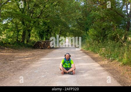 A lonely traveller sitting in the center of the road in italian countryside Stock Photo