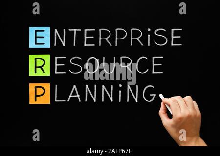 Hand writing the acronym ERP Enterprise Resource Planning with white chalk on blackboard. Stock Photo