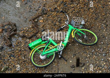 Dockless Lime e-bike, electric bicycle dumped on the bank of the River Thames, London, UK Stock Photo