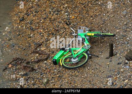 Dockless Lime e-bike, electric bicycle dumped on the bank of the River Thames, London, UK Stock Photo