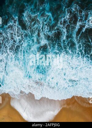 Aerial drone view of beach and ocean waves crashing no people