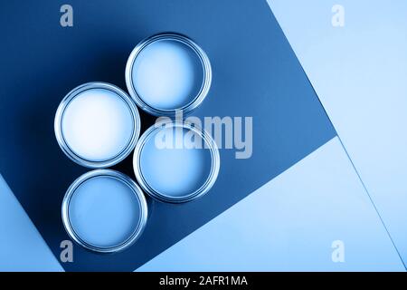 Four open cans on bright background. Yellow, white, pink, turquoise colors of paint. Top view. Renovation concept. Stock Photo