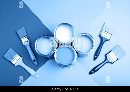 Four open cans of paint with brushes on blue background. Main color of the year 2020 in interior Stock Photo