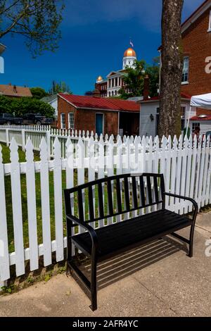 MAY 17 2019, HERMANN MISSOURI USA -white picket fence and bench with old courthouse in background Stock Photo