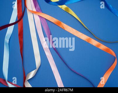 many silk multi-colored ribbons on a blue background, top view Stock Photo