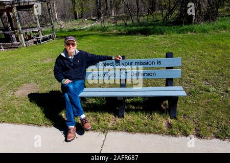 MAY 20, FORT MANDAN, NORTH DAKOTA, USA - Photographer Joe Sohm sits on Thomas Jeffersion quote on bench about 'mission to explore' - Fort Mandan, North Dakota re: Lewis and Clark Expedition Stock Photo