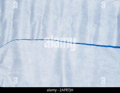 torn piece of white parchment paper on a blue background, close up Stock Photo
