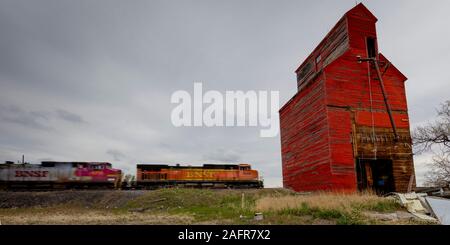 MAY 21,  2019, MONTANA, USA - Freight train drives by Red Grain Silo North Dakota Stock Photo