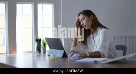 Tired beautiful asian business woman working with headache in modern office room Stock Photo