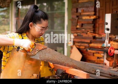 Women standing sawing wooden board on burred background Stock Photo