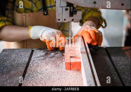 Women standing is craft working cut wood at a work bench with band saws power tools at carpenter machine in the workshop, Worker sawing boards from wi Stock Photo