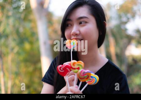 Sweets candies heart shape color full in hand women on blurred background, Set candy of color rainbow lollipops, Gift for valentine day love concepton Stock Photo