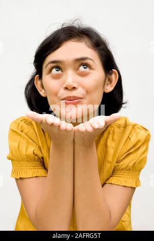 Pretty Southeast Asian young woman blowing her kiss into the air Stock Photo