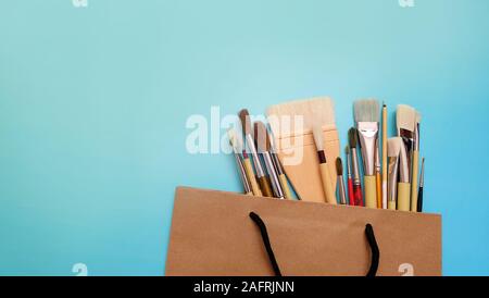 A variety of paint brushes popping out of a brown paper bag. Stock Photo