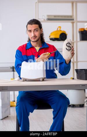 The young male contractor repairing toaster at workshop Stock Photo