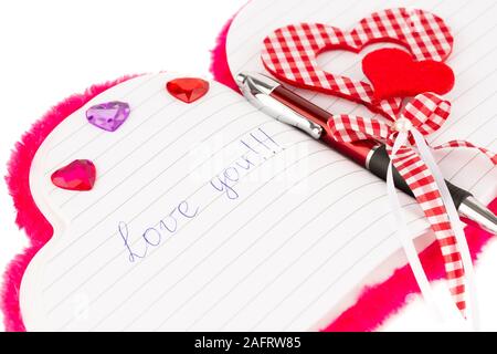 Red hearts, pen  on opened notepad on white background. Inscription Love You. Stock Photo