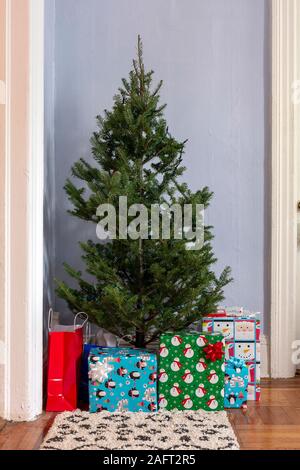 Small Christmas Tree in Corner with Presents Below It in an Apartment Living Room Stock Photo