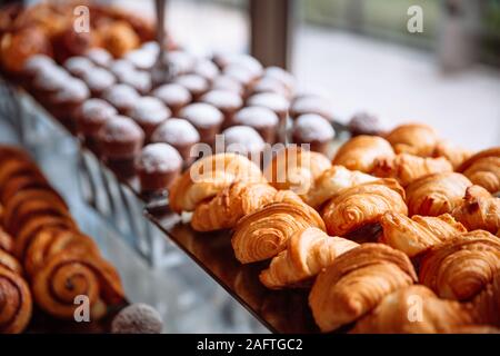 Pastries, croissants and muffins lie on the glass table. Stock Photo