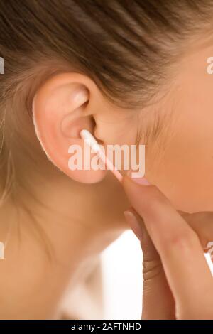 Closeup of woman cleaning her ear with cotton swab Stock Photo