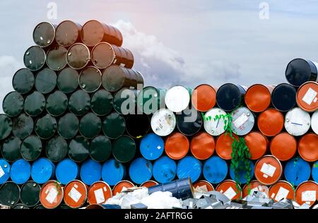 Old chemical barrels. Blue, orange, and black oil drum. Steel oil tank. Toxic waste warehouse. Hazard chemical barrel. Industrial waste in metal drum. Stock Photo