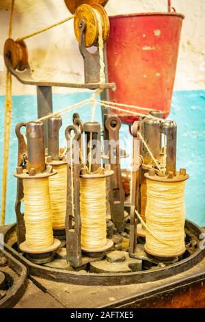 Vintage industrial braiding machine with bobbins of twine & pulleys in a textile museum Masson Mills Museum Derbyshire UK Stock Photo