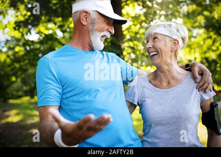 Beautiful senior couple running outside in forest Stock Photo