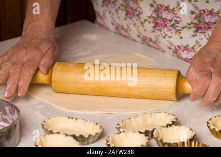 woman preparing dough with rolling pin on rustic wooden table Stock Photo