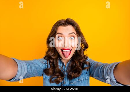 Photo of curly wavy cheerful charming nice girl sticking tongue out taking selfie playful isolated over yellow vivid color background Stock Photo