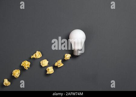 Creativity inspiration, great business idea concept with white light bulb and paper crumpled ball on gray background. Flat lay, top view, copy space Stock Photo
