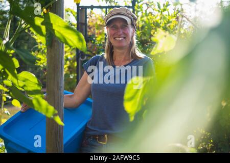 Portrait confident smiling farmer in sunny vegetable garden Stock Photo