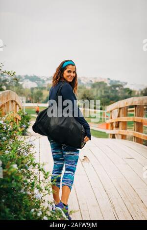 Portrait confident female personal trainer walking over footbridge in park Stock Photo